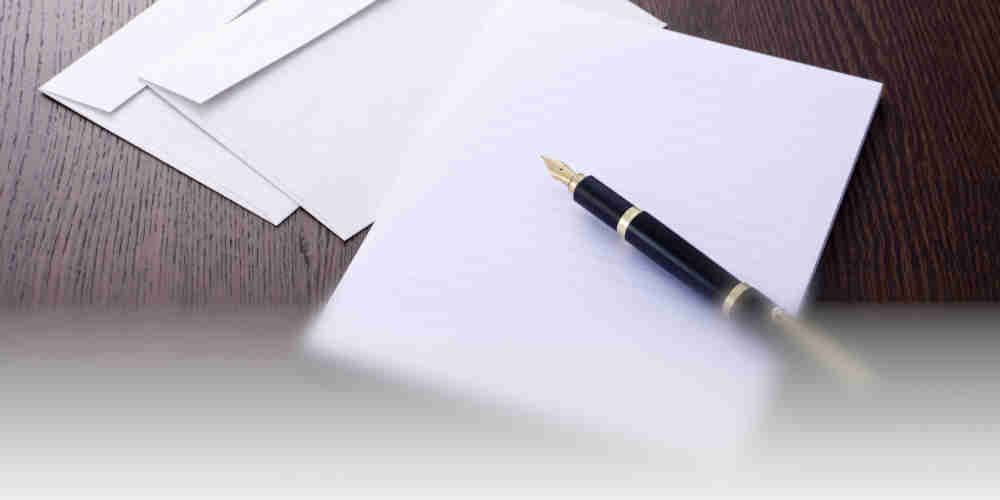 Office desk with paper and pen ready to write